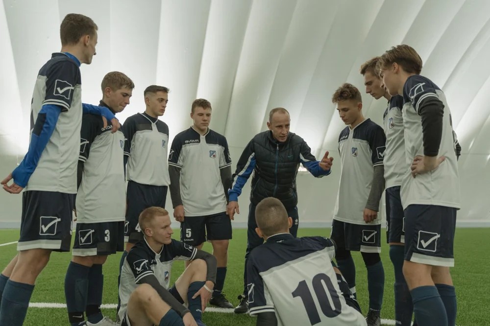 A coach speaking with athletes during a team training session.
