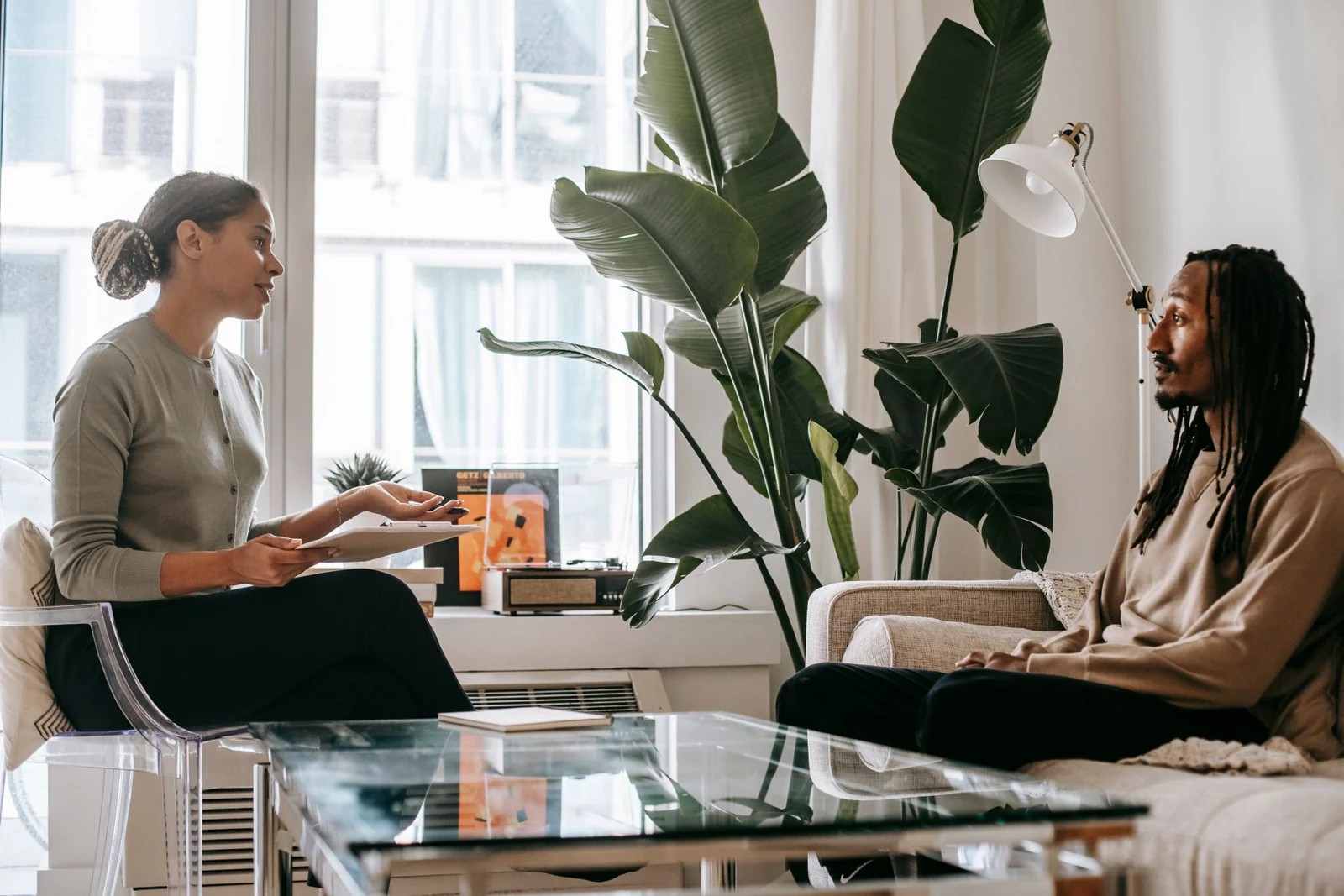 Two adults talking in a bright consultation room, with a notebook between them.